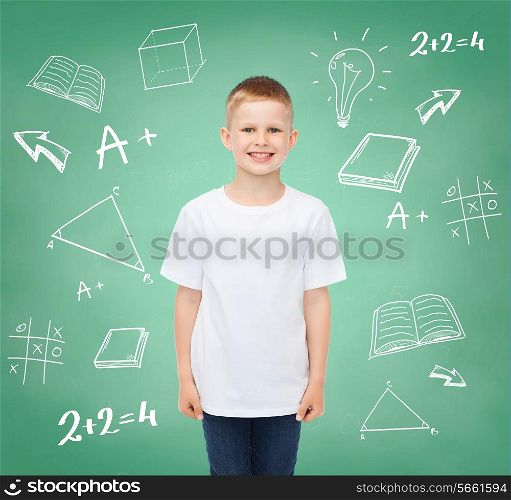 happiness, childhood, school education, advertisement and people concept - smiling little boy in white t-shirt over green board with doodles background