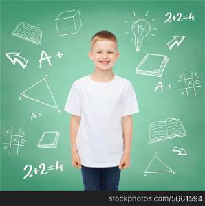 happiness, childhood, school education, advertisement and people concept - smiling little boy in white t-shirt over green board with doodles background