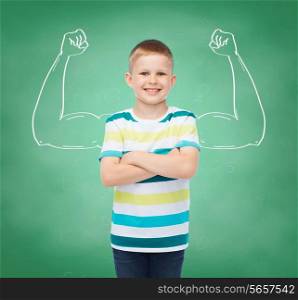 happiness, childhood, school, education and people concept - smiling little boy in casual clothes over green board background strong arms drawing