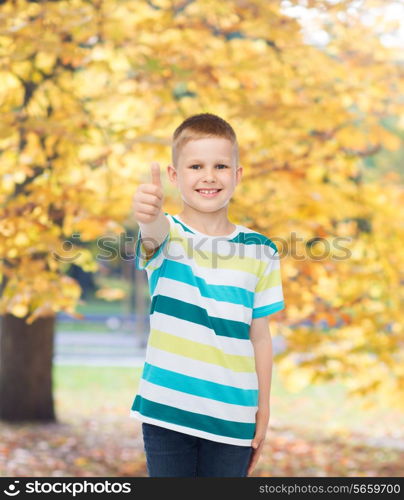 happiness, childhood, seasons and people concept - smiling little boy in casual clothes showing thumbs up over autumn park background