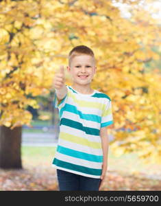 happiness, childhood, seasons and people concept - smiling little boy in casual clothes showing thumbs up over autumn park background