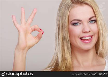 Happiness concept. Happy woman showing ok hand sign gesture on gray background