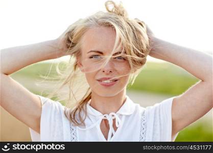happiness, country, summer holidays, vacation and people concept - close up of happy smiling young woman or teenage girl with wild hair outdoors