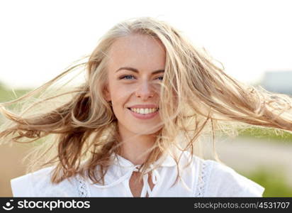 happiness, country, summer holidays, vacation and people concept - close up of happy smiling young woman or teenage girl with wild hair outdoors