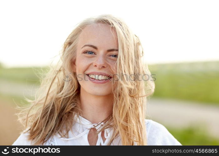 happiness, country, summer holidays, vacation and people concept - close up of happy smiling young woman or teenage girl with wild hair outdoors