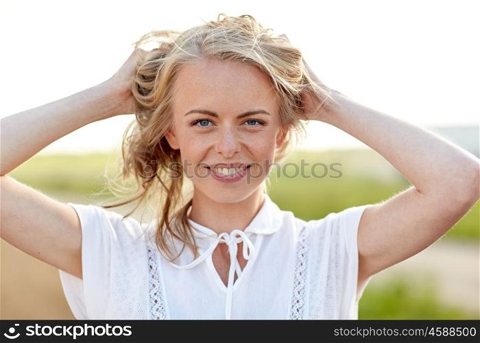 happiness, country, summer holidays, vacation and people concept - close up of happy smiling young woman or teenage girl with wild hair outdoors