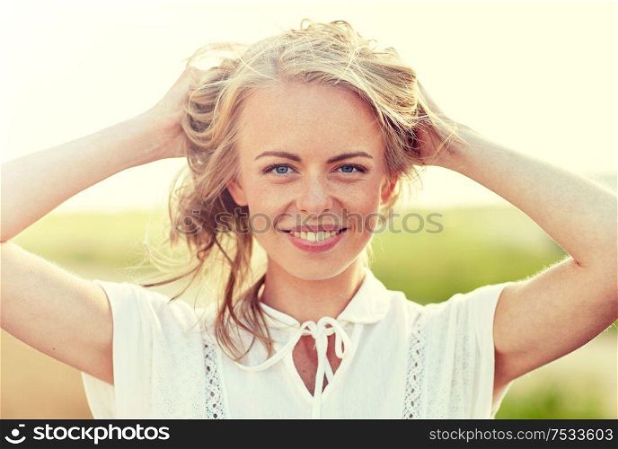 happiness, country, summer holidays, vacation and people concept - close up of happy smiling young woman or teenage girl with wild hair outdoors. close up of happy young woman in white outdoors