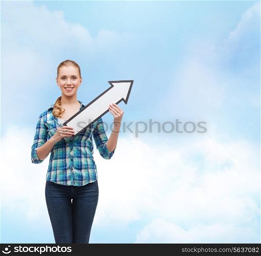 happiness, direction and people concept - smiling young woman arrow poiting up over blue sky background