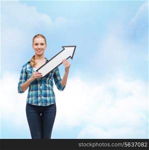 happiness, direction and people concept - smiling young woman arrow poiting up over blue sky background