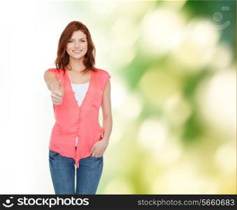 happiness, ecology, gesture and people concept - smiling teenage girl in casual clothes showing thumbs up over green background