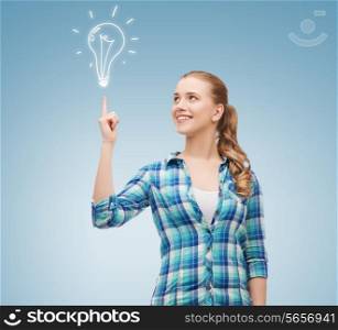happiness, electricity, idea and people concept - smiling young woman pointing finger up to electric bulb over blue background