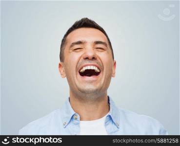 happiness, emotions and people concept - laughing man over gray background