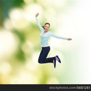 happiness, freedom, ecology and people concept - smiling young woman jumping in air over green background