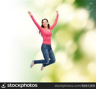 happiness, freedom, ecology and people concept - smiling young woman jumping in air over green background