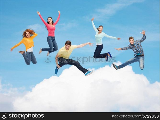 happiness, freedom, friendship, movement and people concept - group of smiling teenagers jumping in air over blue sky with white cloud background