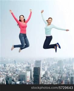 happiness, freedom, friendship, movement and people concept - smiling young women jumping in air over city background