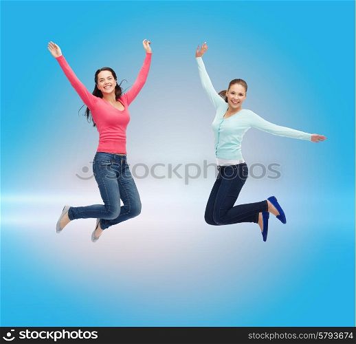 happiness, freedom, friendship, movement and people concept - smiling young women jumping in air over blue laser background