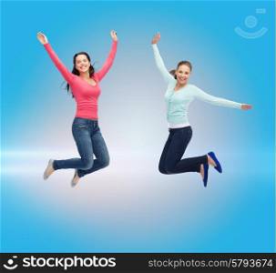 happiness, freedom, friendship, movement and people concept - smiling young women jumping in air over blue laser background
