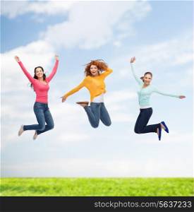 happiness, freedom, friendship, summer and people concept - group of smiling young women jumping in air over natural background