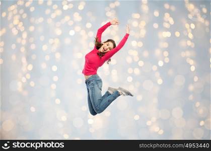 happiness, freedom, motion and people concept - happy young woman jumping or dancing in air over holidays lights background. happy young woman jumping or dancing over lights