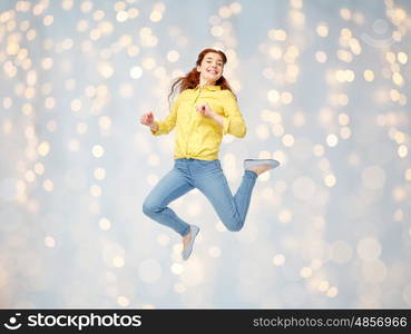 happiness, freedom, motion and people concept - smiling young woman jumping in air over holidays lights background