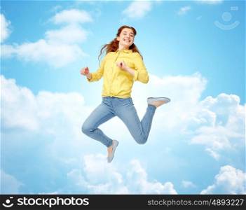 happiness, freedom, motion and people concept - smiling young woman jumping in air over blue sky and clouds background
