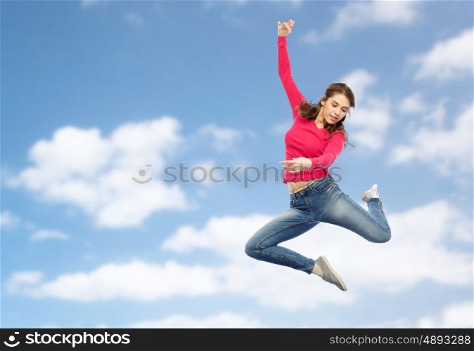 happiness, freedom, motion and people concept - smiling young woman jumping in air over blue sky and clouds background