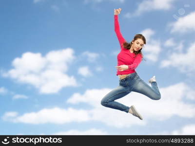 happiness, freedom, motion and people concept - smiling young woman jumping in air over blue sky and clouds background