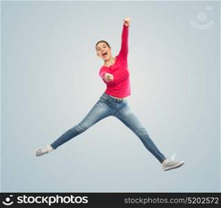 happiness, freedom, motion and people concept - smiling young woman jumping in air and pointing finger to you over blue background. smiling young woman jumping in air