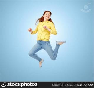 happiness, freedom, motion and people concept - smiling young woman jumping in air over blue background. smiling young woman jumping in air