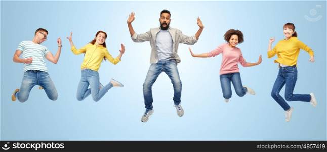 happiness, freedom, motion, diversity and people concept - international group of happy smiling men and women jumping over blue background