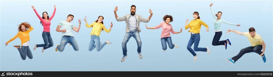 happiness, freedom, motion, diversity and people concept - international group of happy smiling men and women jumping over blue background. international group of happy people jumping