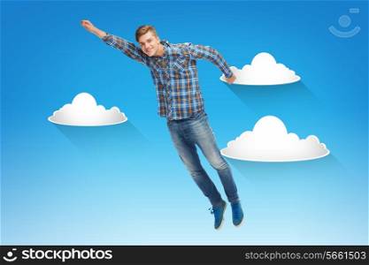 happiness, freedom, movement and people concept - smiling young man flying in air over blue sky with white clouds background