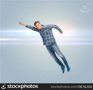 happiness, freedom, movement and people concept - smiling young man flying in air over gray background with laser light