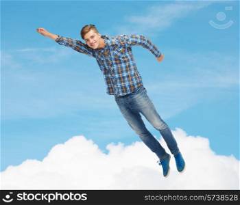 happiness, freedom, movement and people concept - smiling young man flying in air over blue sky with white cloud background