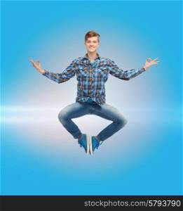 happiness, freedom, movement and people concept - smiling young man hanging of flying in air over blue laser background