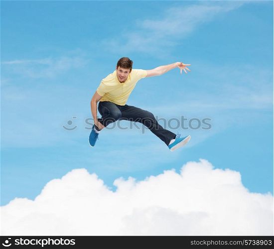 happiness, freedom, movement and people concept - smiling young man jumping in air over blue sky with white cloud background