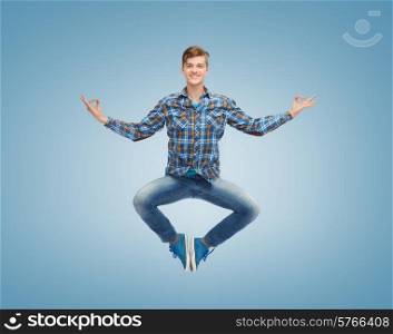 happiness, freedom, movement and people concept - smiling young man jumping in air over blue background