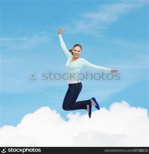 happiness, freedom, movement and people concept - smiling young woman jumping in air over blue sky with white cloud background