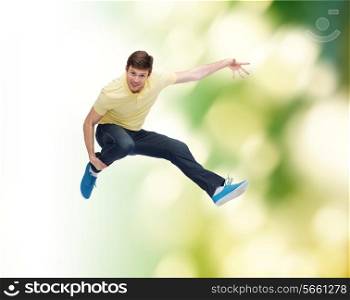 happiness, freedom, movement, ecology and people concept - smiling young man jumping in air over green background