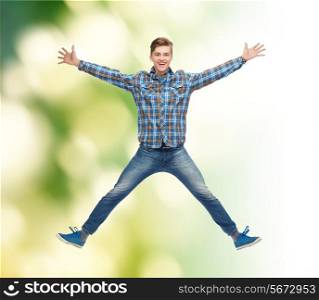 happiness, freedom, movement, ecology and people concept - smiling young man jumping in air over green background
