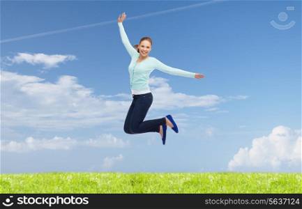 happiness, freedom, movement, summer and people concept - smiling young woman jumping in air over natural background