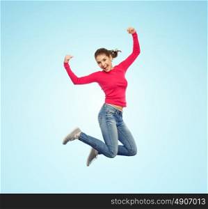 happiness, freedom, power, motion and people concept - smiling young woman jumping in air with raised fists over blue background. smiling young woman jumping in air