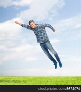happiness, freedom, vacation, summer and people concept - smiling young man flying in air over natural background