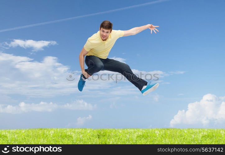 happiness, freedom, vacation, summer and people concept - smiling young man jumping in air over natural background