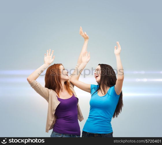 happiness, friendship and people concept - smiling teenage girls having fun over gray background with laser light