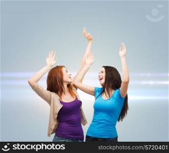 happiness, friendship and people concept - smiling teenage girls having fun over gray background with laser light