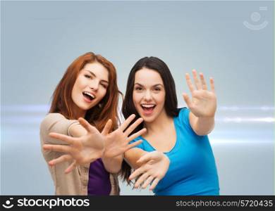 happiness, friendship and people concept - smiling teenage girls having fun over gray background with laser light
