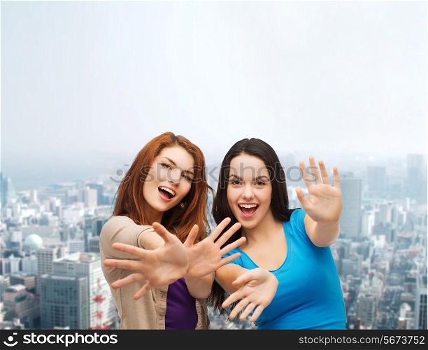 happiness, friendship and people concept - smiling teenage girls having fun over city background