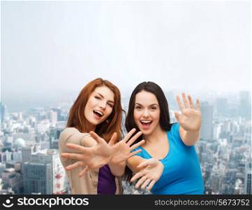 happiness, friendship and people concept - smiling teenage girls having fun over city background